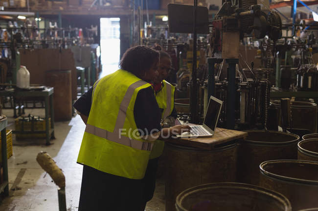 Trabalhadores discutindo sobre um laptop na indústria de fabricação de cordas — Fotografia de Stock