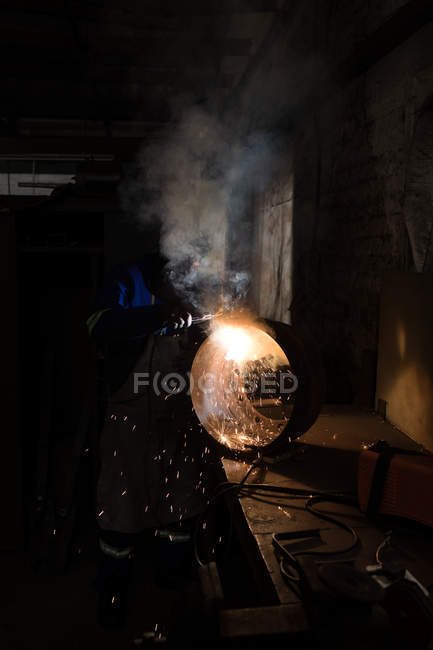 Forgeron attentif à l'aide d'une torche de soudage en atelier — Photo de stock