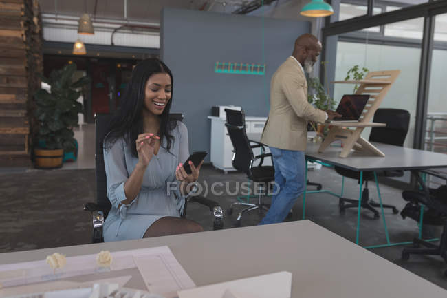 Женщина-руководитель с помощью мобильного телефона за столом в офисе — стоковое фото