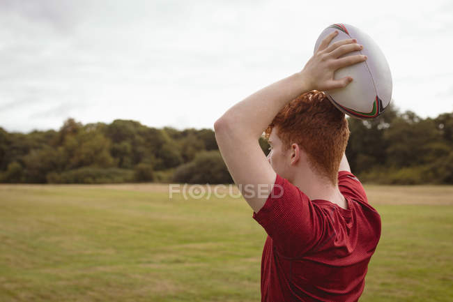 Jeune joueur de rugby prêt à lancer une balle de rugby sur le terrain — Photo de stock