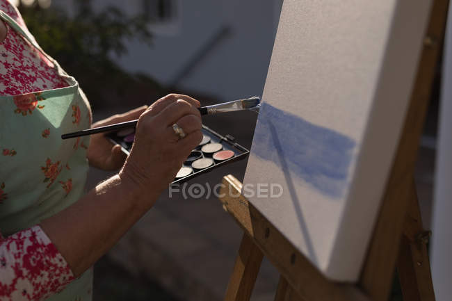 Nahaufnahme einer Seniorin beim Malen auf Leinwand im Garten — Stockfoto