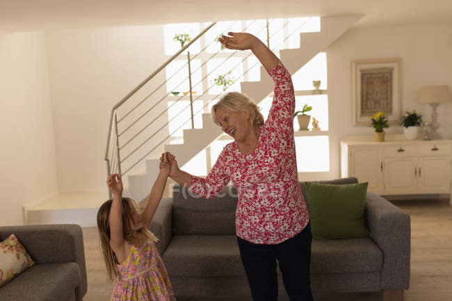 Grandmother and granddaughter dancing in living room at home — Stock Photo