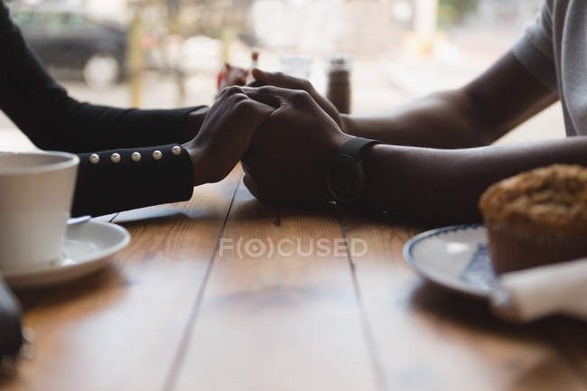 Primer plano de pareja cogida de la mano en la cafetería - foto de stock