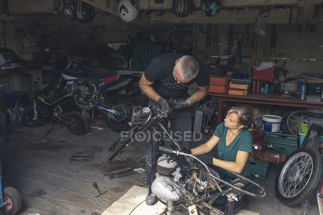 Male and female mechanicians repairing motorbike in repair garage — Stock Photo