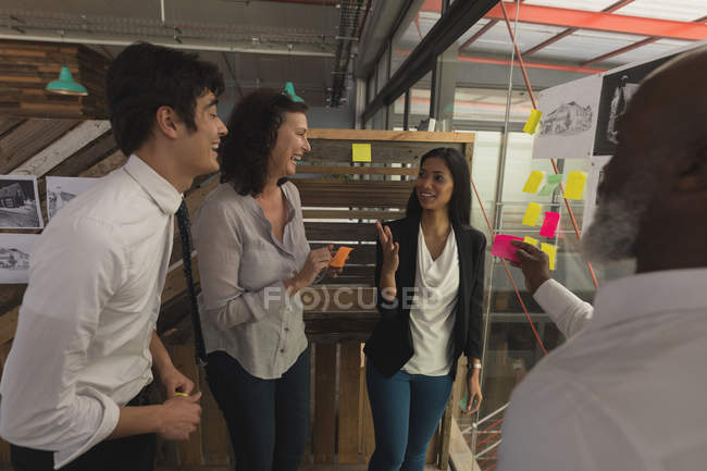 Business executives discussing over a sticky notes at office — Stock Photo