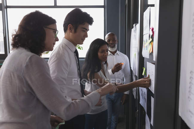 Führungskräfte diskutieren im Büro über einen klebrigen Zettel — Stockfoto