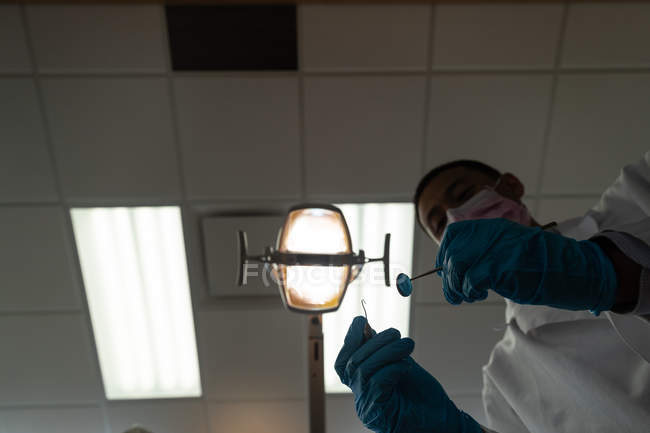 Низький кут зору стоматолога, який тримає інструменти в стоматологічному кабінеті — стокове фото
