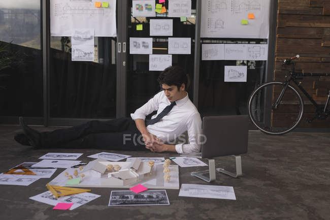 Smart male executive looking house model and charts in office — Stock Photo