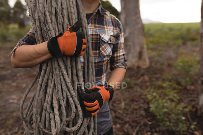 Mid section of lumberjack holding rope in forest — Stock Photo