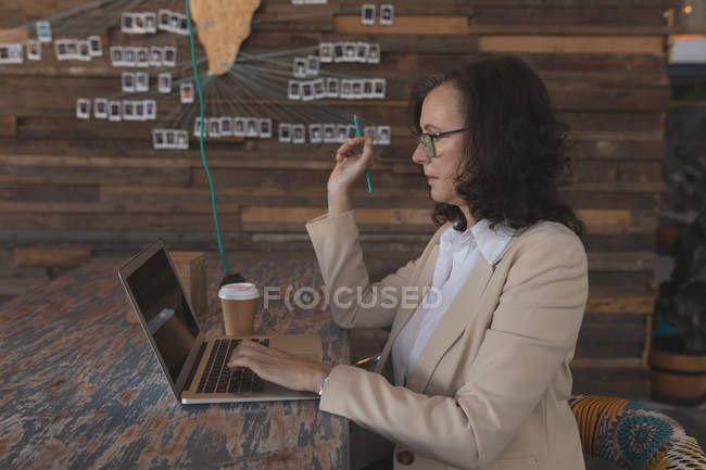 Female executive working on laptop at table in office — Stock Photo