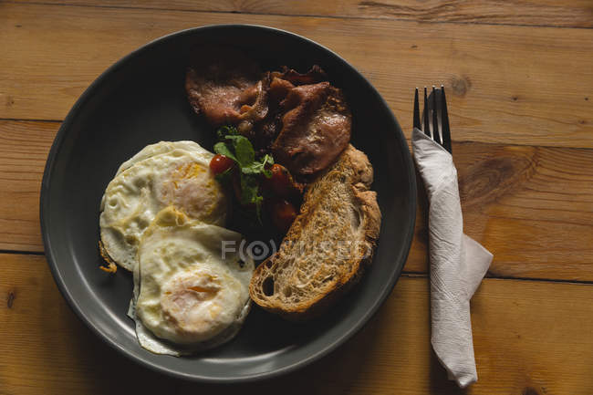 Яйца жареные и тосты подаются в тарелке в кафе — стоковое фото