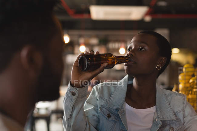 Mujer joven tomando cerveza en la cafetería - foto de stock