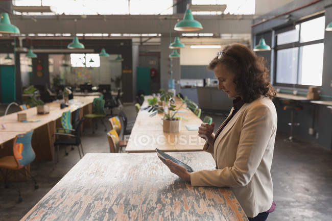 Esecutivo femminile che utilizza tablet digitale al tavolo in ufficio — Foto stock