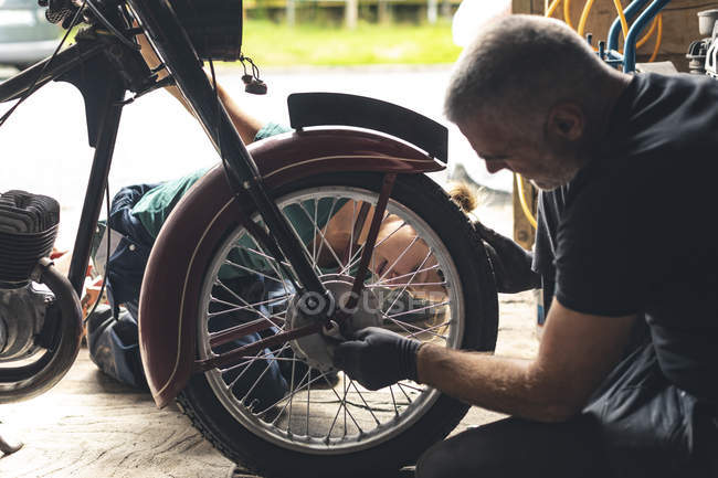 Mechanic repairing motorbike in repair garage — Stock Photo