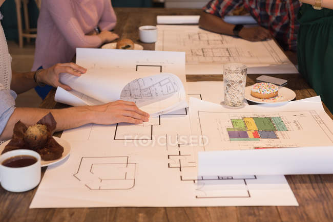 Mid section of business people discussing blueprints in the office — Stock Photo