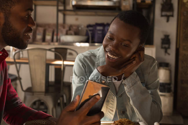 Happy couple using mobile phone in cafe — Stock Photo