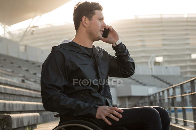 Спортсмен-инвалид разговаривает по мобильному телефону на спортивном объекте — стоковое фото