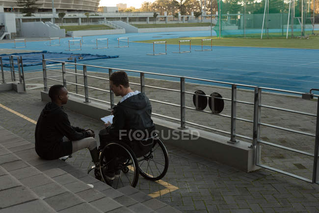 Two disabled athlete discussing over clipboard at sports venue — Stock Photo