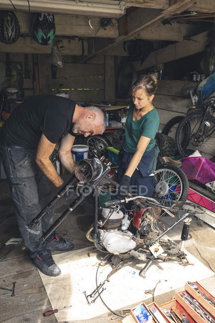 Mecanicistas masculinos e femininos reparando moto na garagem de reparação — Fotografia de Stock