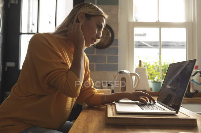 Концентрована вагітна жінка використовує ноутбук вдома — стокове фото