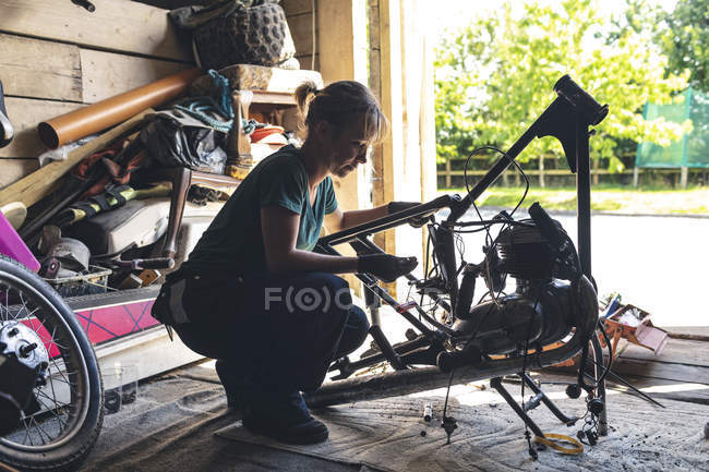 Female mechanic repairing motorbike in garage — Stock Photo