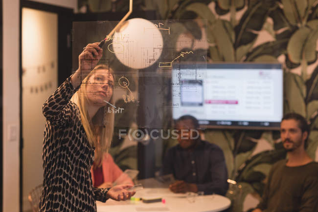Empresária fazendo uma apresentação para seus colegas no escritório — Fotografia de Stock