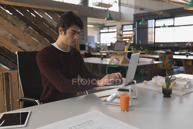 Male executive working on laptop in office — Stock Photo