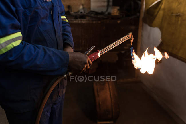 Mid section of blacksmith using a welding torch in workshop — Stock Photo