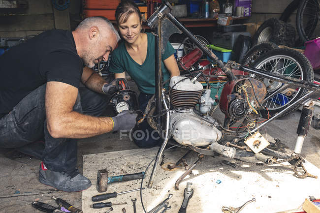Чоловічий і жіночий mechanicians, ремонт мотоцикл в ремонт гаража — стокове фото