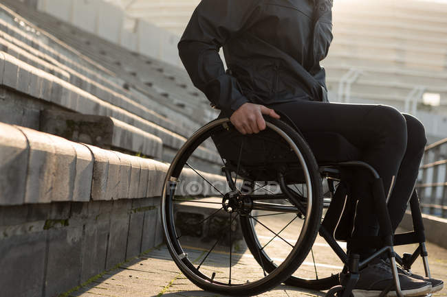 Sección baja del atleta discapacitado que se mueve con silla de ruedas en un lugar deportivo - foto de stock