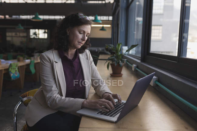 Executivo feminino trabalhando no laptop à mesa no escritório — Fotografia de Stock