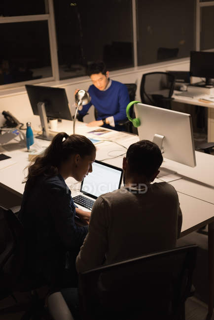 Three business people working on laptop in office during nighttime — Stock Photo