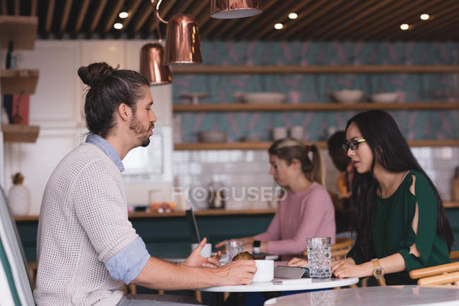 Businessman and businesswoman discussing in the cafeteria in office — Stock Photo