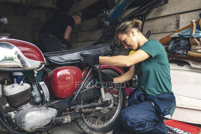 Femme mécanicien réparation moto dans le garage — Photo de stock