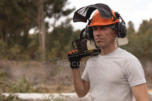 Lumberjack holding chainsaw in the forest at countryside — Stock Photo