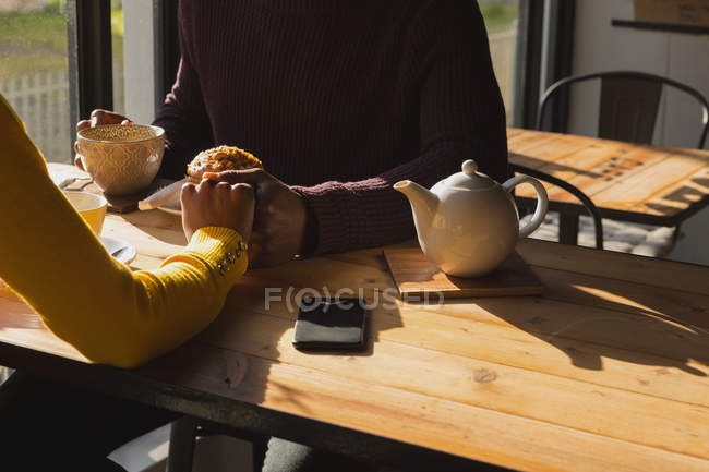 Mid section of couple holding hand in cafe — Stock Photo