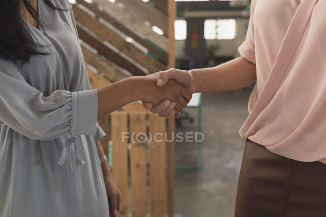 Sezione media di dirigenti femminili che si stringono la mano in ufficio — Foto stock