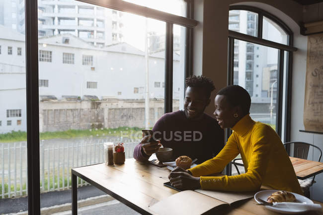 Glückliches Paar benutzt Handy im Café — Stockfoto