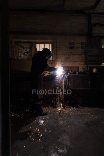 Side view of blacksmith using a welding torch in workshop — Stock Photo