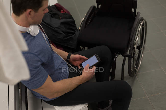 Disabled man using mobile phone in changing room — Stock Photo