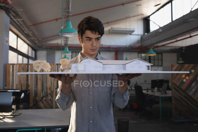 Чоловік-виконавчий, що працює над моделлю будинку в офісі — стокове фото