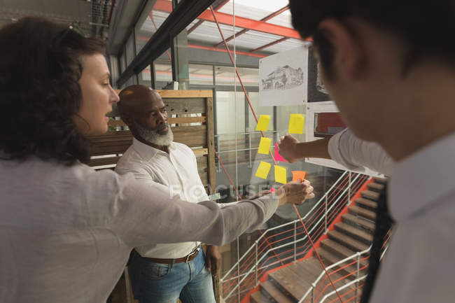 Business executives discussing over a sticky notes at office — Stock Photo