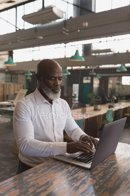 Ejecutivo masculino trabajando en el ordenador portátil en la oficina - foto de stock