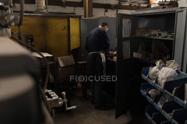 Vista posteriore del fabbro che lavora in officina — Foto stock