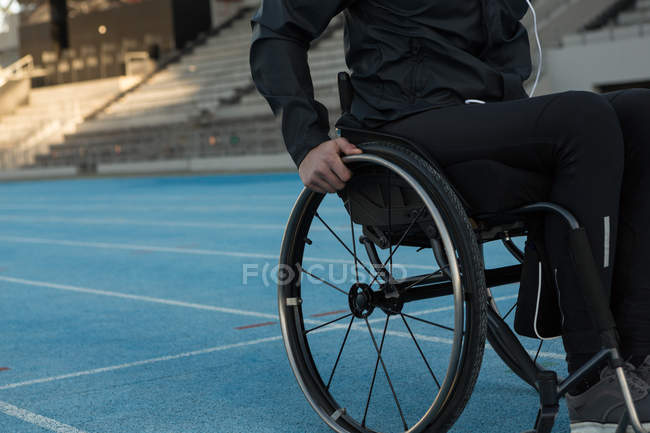 Средняя секция спортсмена-инвалида, движущегося с инвалидной коляской на спортивном объекте — стоковое фото