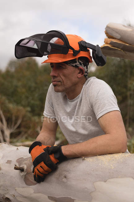 Nahaufnahme eines Holzfällers, der sich im Wald an einen Baumstamm lehnt — Stockfoto
