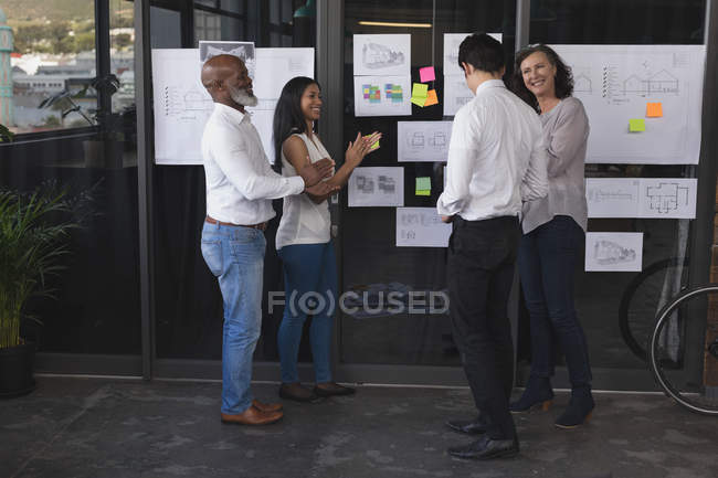 Happy business executives interacting with each other in office — Stock Photo
