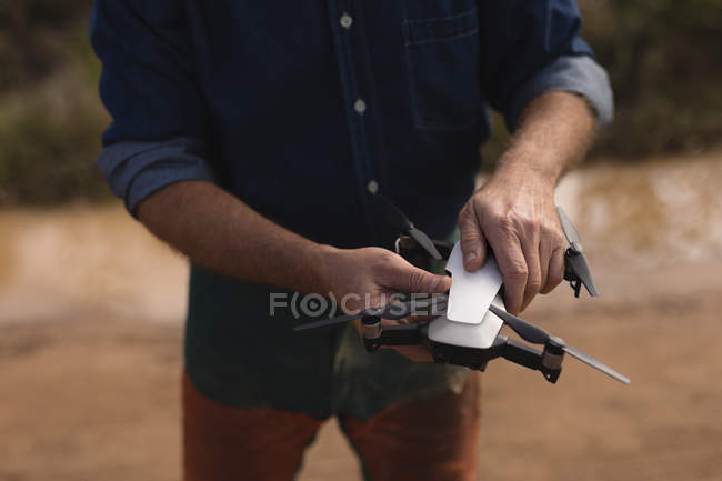 Mid section of lumberjack holding drone in forest — Stock Photo