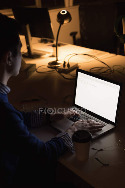 Крупный план бизнесмена, работающего на ноутбуке в офисе ночью — стоковое фото