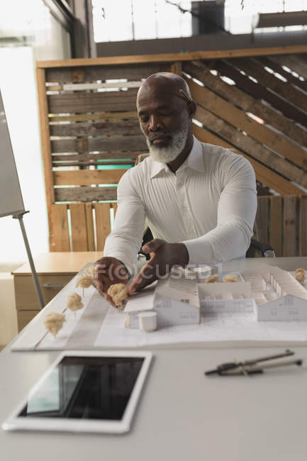Male executive working on house model in office — Stock Photo